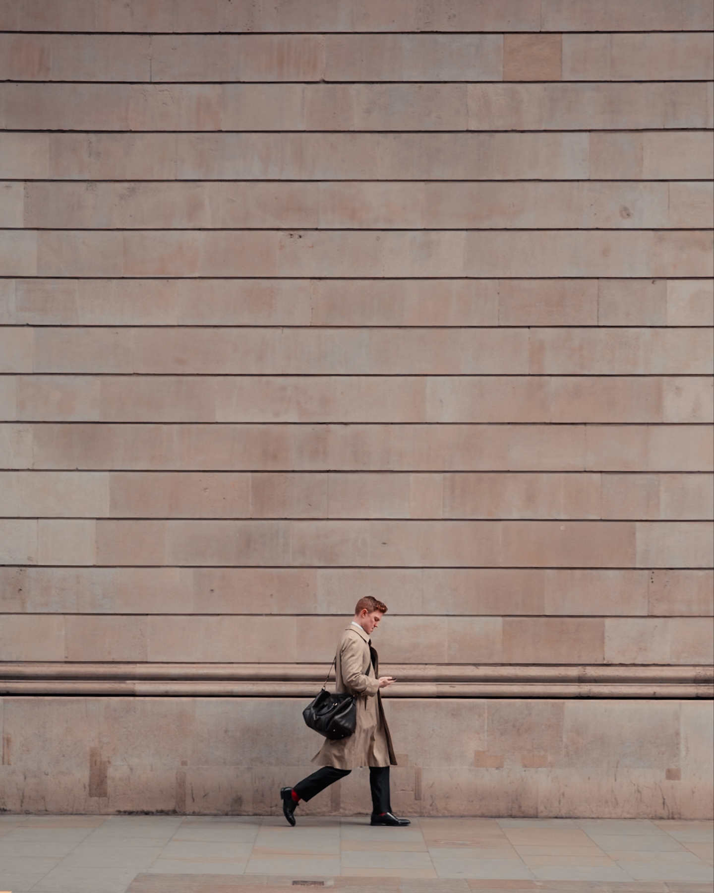 a sole business man looking small against a giant plain wall