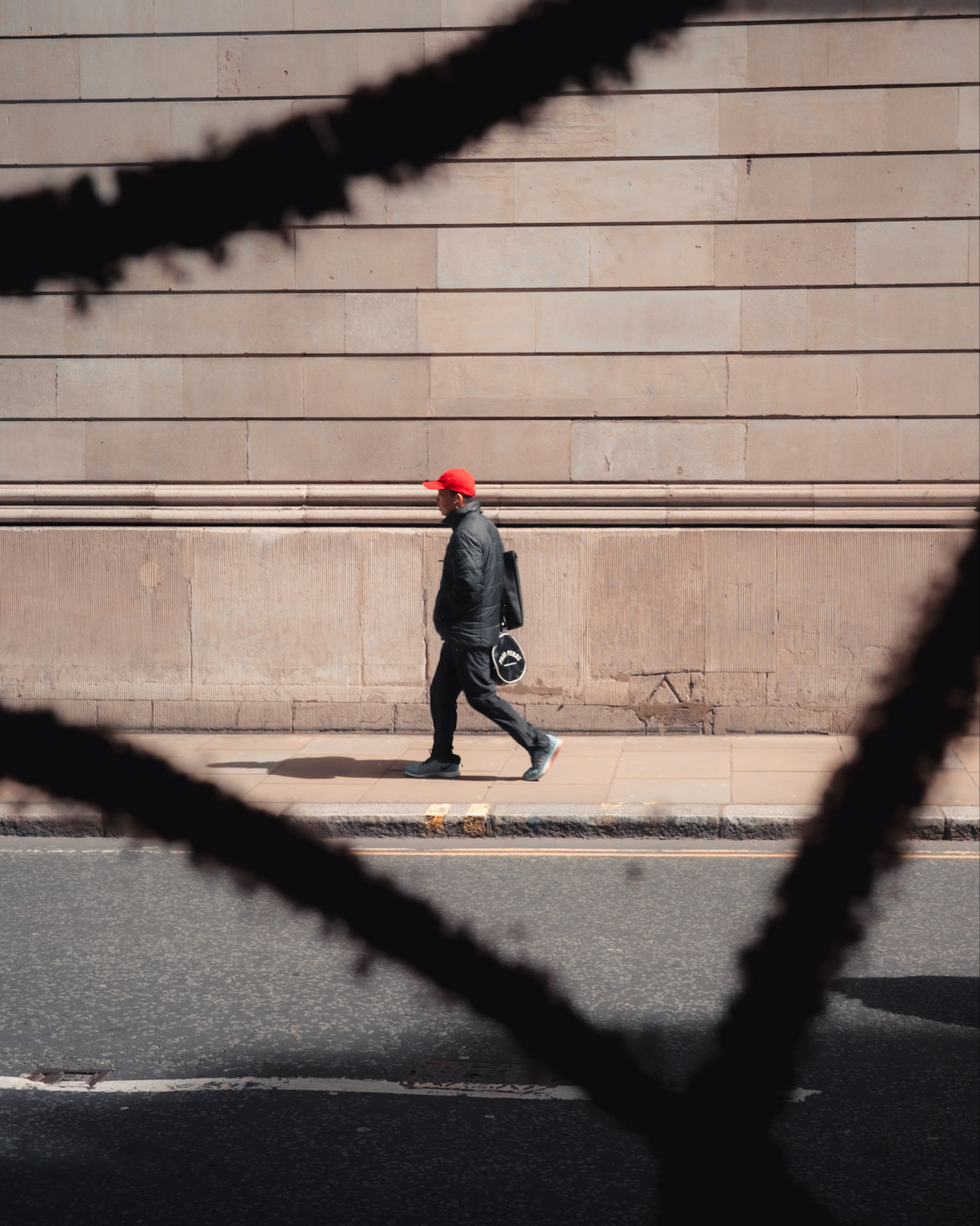 a man wearing a red hat shot through a gap in graffiti